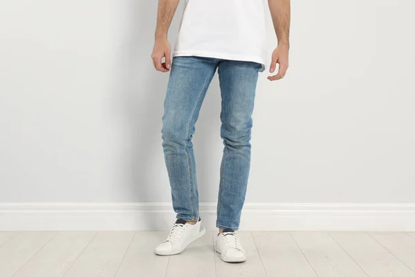 Ung man i snygga jeans nära ljus vägg, närbild — Stockfoto