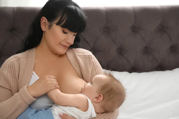 Жінка грудного вигодовування її маленька дитина на ліжку в приміщенні — стокове фото
