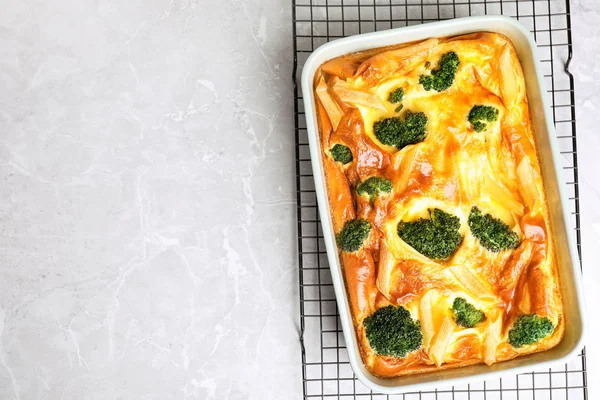 Tasty broccoli casserole in baking dish on cooling rack, top vie — Stock Photo, Image