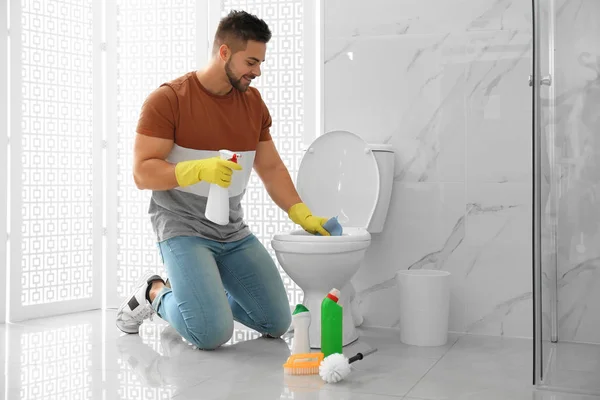 Jongeman schoonmaken toilet kom in badkamer — Stockfoto