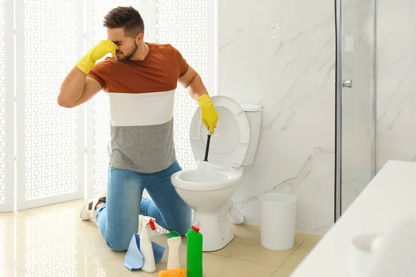 Jongeman voelt walging tijdens het schoonmaken van toilet kom in de badkamer — Stockfoto