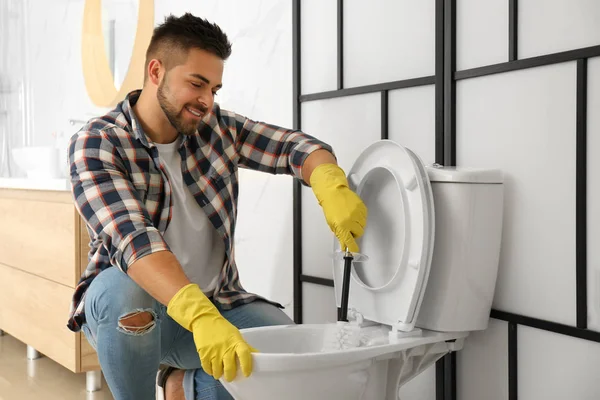 Jongeman schoonmaken toilet kom in badkamer — Stockfoto