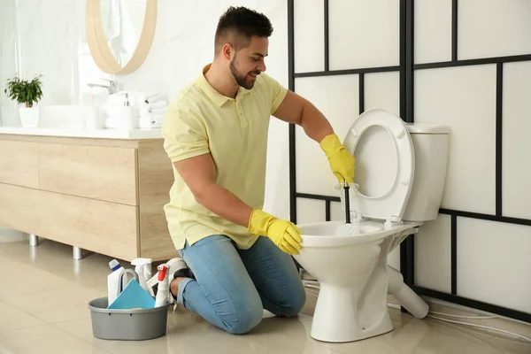 Joven hombre limpieza inodoro en cuarto de baño — Foto de Stock