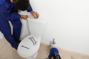 Profesyonel tesisatçı tuvalette klozetle çalışıyor.