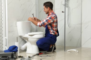 Profesyonel tesisatçı tuvalette klozetle çalışıyor.