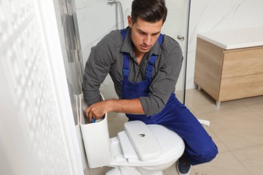 Profesyonel tesisatçı tuvalette klozetle çalışıyor.