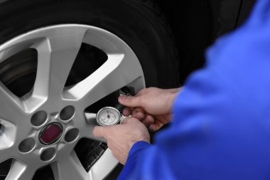 Tamirci araba servisinde lastik basıncını kontrol ediyor.