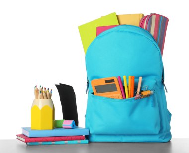 Bright backpack with school stationery on grey stone table again clipart
