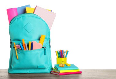 Bright backpack with school stationery on wooden table against w clipart