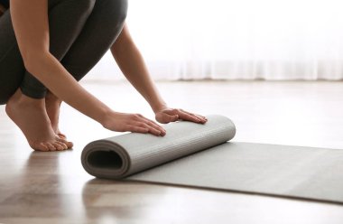 Stüdyoda yoga minderi yuvarlayan kadın, yakın plan.