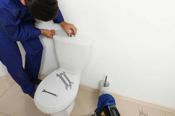 Profesjonalny hydraulik pracujący z muszlą klozetową w łazience — Zdjęcie stockowe