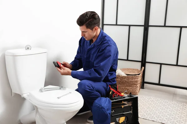 Professional plumber working with toilet bowl in bathroom — Stock Photo, Image