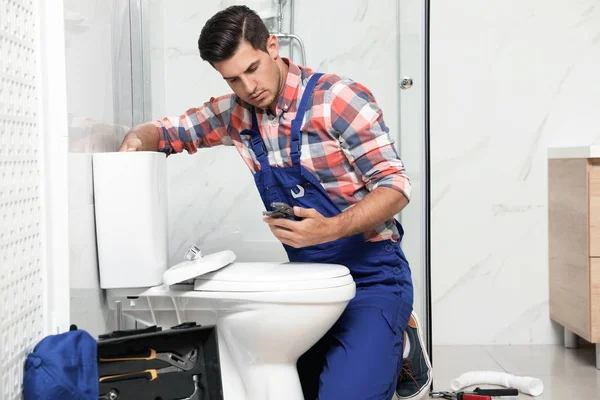 Encanador profissional trabalhando com vaso sanitário no banheiro — Fotografia de Stock