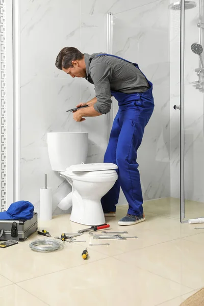 Plombier professionnel travaillant avec cuvette de toilette dans la salle de bains — Photo
