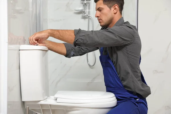 Fontanero profesional trabajando con inodoro en el baño — Foto de Stock