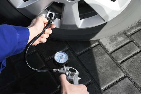 Mechanic checking tire air pressure at car service, closeup