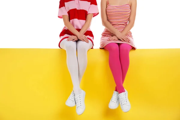 Las mujeres que usan medias brillantes sentadas en el fondo de color, primer plano — Foto de Stock