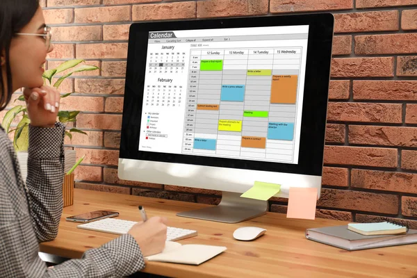 Mujer usando la aplicación de calendario en el ordenador en la oficina, primer plano —  Fotos de Stock