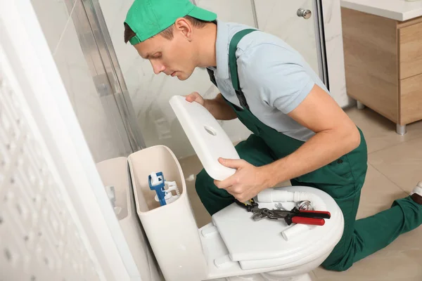 Professional plumber repairing toilet tank in bathroom — Stock Photo, Image