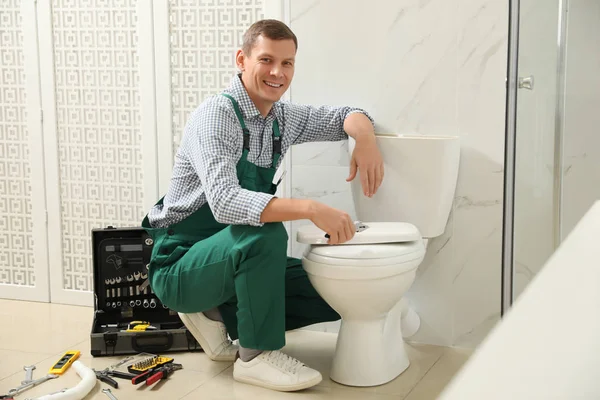 Professional plumber repairing toilet bowl in bathroom — Stock Photo, Image
