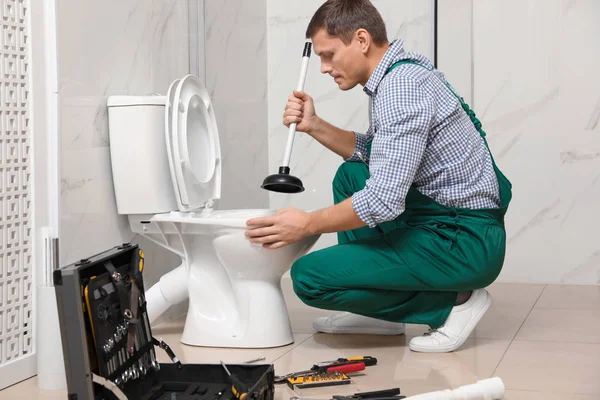 Профессиональный сантехник расчищает канализацию унитаза в ванной комнате — стоковое фото