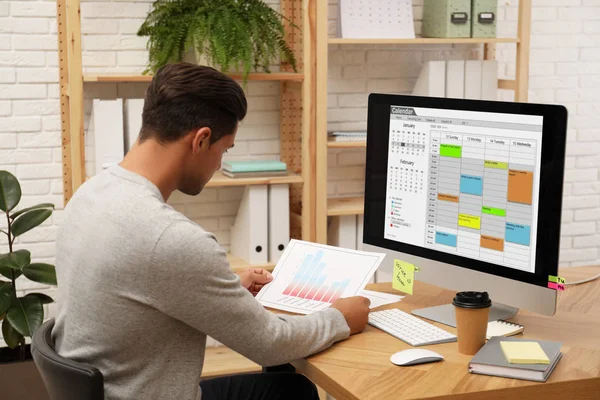 Knappe man met behulp van kalender app op de computer in het kantoor — Stockfoto