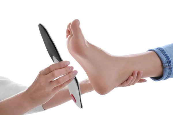 Orthopedist fitting insole on patient's foot against white backg — Stock Photo, Image