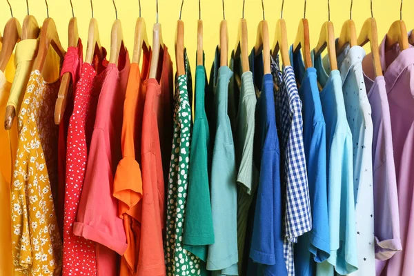 Helle Kleidung Auf Kleiderbügeln Vor Gelbem Hintergrund Nahaufnahme Regenbogenfarben — Stockfoto