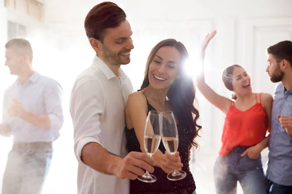 Adorável jovem casal com copos de champanhe na festa de dança — Fotografia de Stock