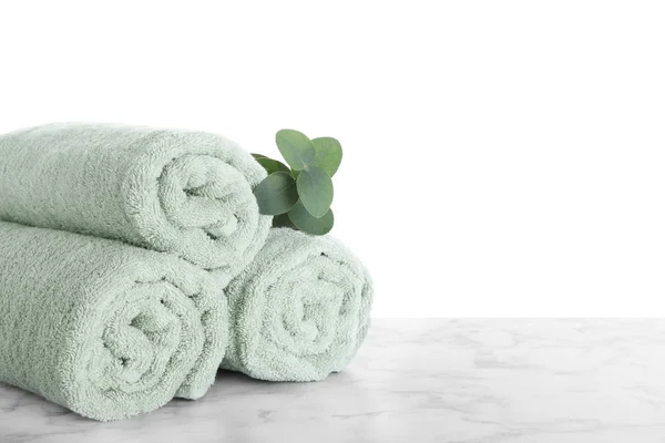 Fresh towels and eucalyptus branch on marble table against white — Stock Photo, Image