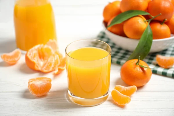 Glass of fresh tangerine juice and fruits on white wooden table — Stock Photo, Image