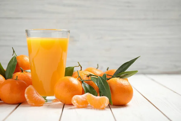 Glass of fresh tangerine juice and fruits on white wooden table — Stock Photo, Image