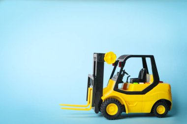 Mavi arkaplanda oyuncak forklift, metin için boşluk. Lojistik ve toptan satış kavramı