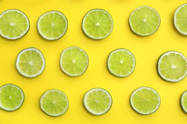 Sarı arka planda taze sulu limon dilimleri, düz uzanmış.