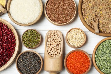 Farklı tipte baklagiller ve tahıl gevrekleri beyaz ahşap masa, düz yatak. Organik taneler