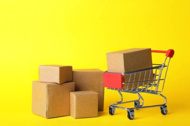Alışveriş arabası ve sarı arka planda kutular. Lojistik ve toptan satış kavramı