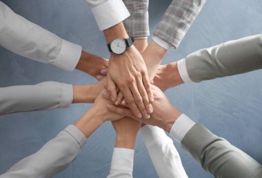 Gri taş arka planda el ele tutuşan insanlar, üst manzara. Birlik kavramı