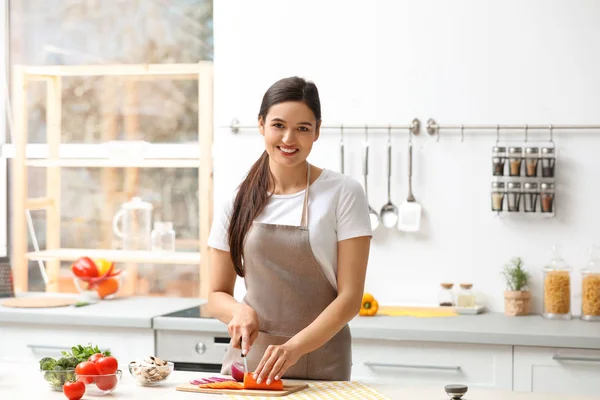 Молодая женщина режет овощи для супа за столом на кухне — стоковое фото