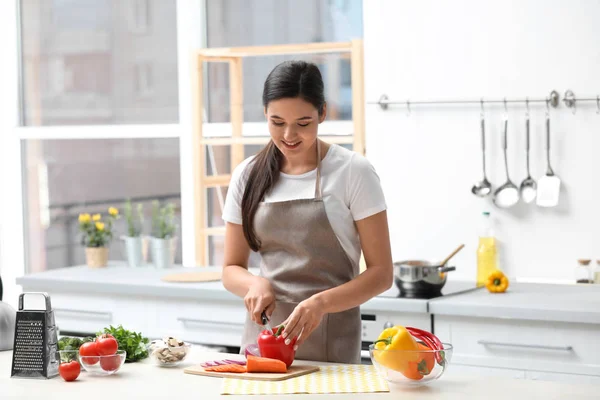 Молодая женщина режет овощи для супа за столом на кухне — стоковое фото