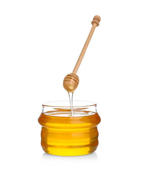 Honey dripping from wooden dipper into jar isolated on white — Stock Photo, Image