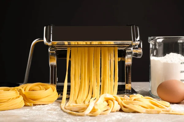 Máquina de hacer pasta con masa y productos en gris mesa agains — Foto de Stock