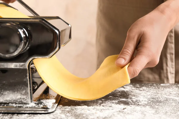 Mujer preparando masa con máquina de hacer pasta en la mesa, primer plano — Foto de Stock