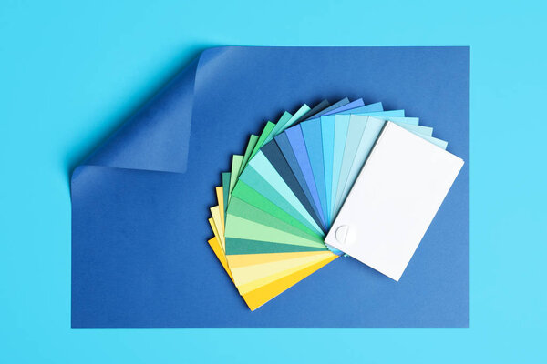 Color palette and bright paper on light blue background, top vie