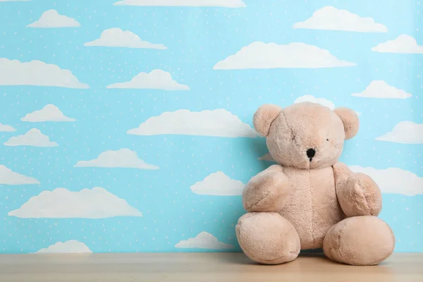 Teddy bear on wooden table near wall with painted blue sky, spac — Stock Photo, Image