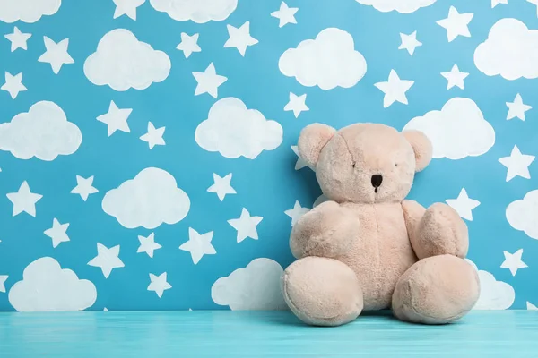 Teddybär auf Holztisch neben Wand mit gemaltem blauem Himmel, spac — Stockfoto