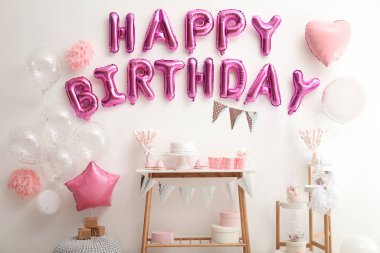 Beyaz duvardaki pembe balon harflerinden oluşan mutlu yıllar deyimi