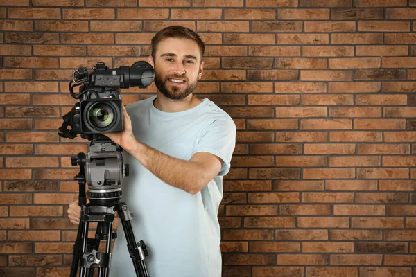 Operator z profesjonalną kamerą wideo w pobliżu ściany z cegły, przestrzeń f — Zdjęcie stockowe