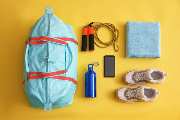 Gym bag, smartphone and sports equipment on yellow background, f — Stock Photo, Image