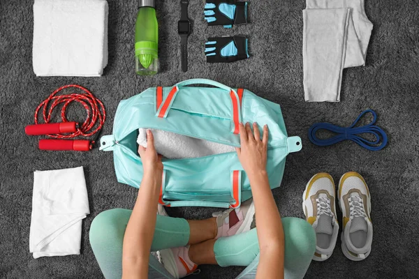 Женщина с сумкой и спортивными предметами на сером ковре, вид сверху — стоковое фото