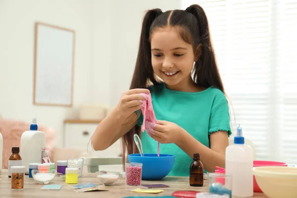 Linda niña haciendo juguete de limo DIY en la mesa en el interior — Foto de Stock